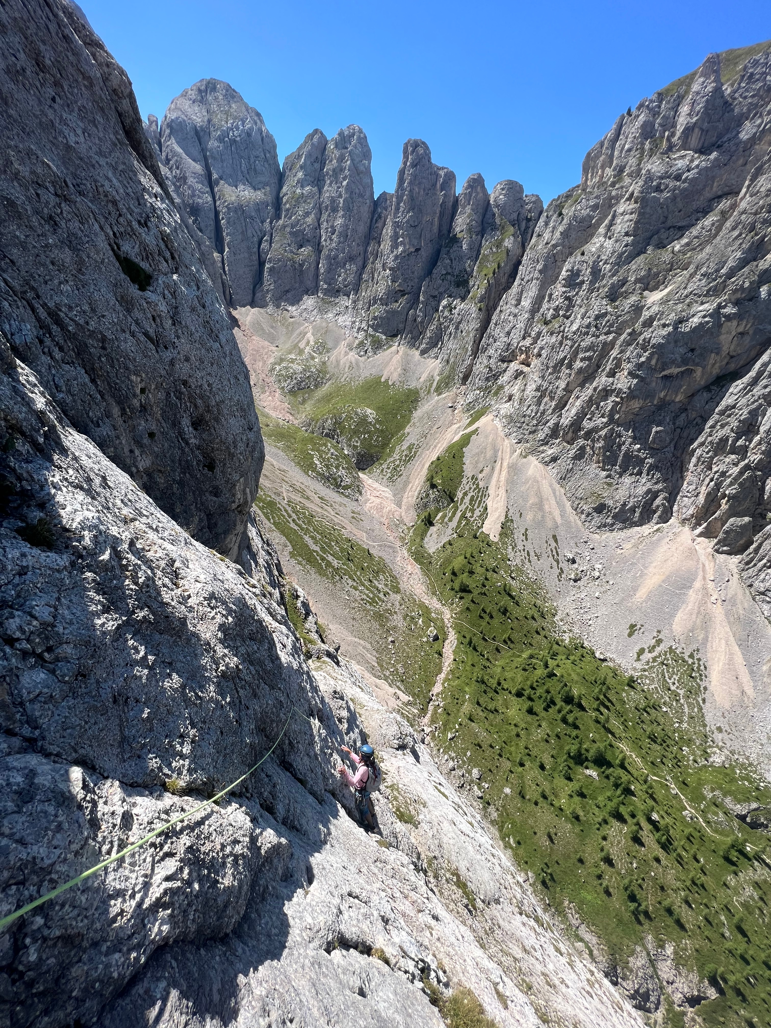 Alpinklettern Dolomiten: Kletterin an Felswand mit charakteristischen Türmen im Hintergrund